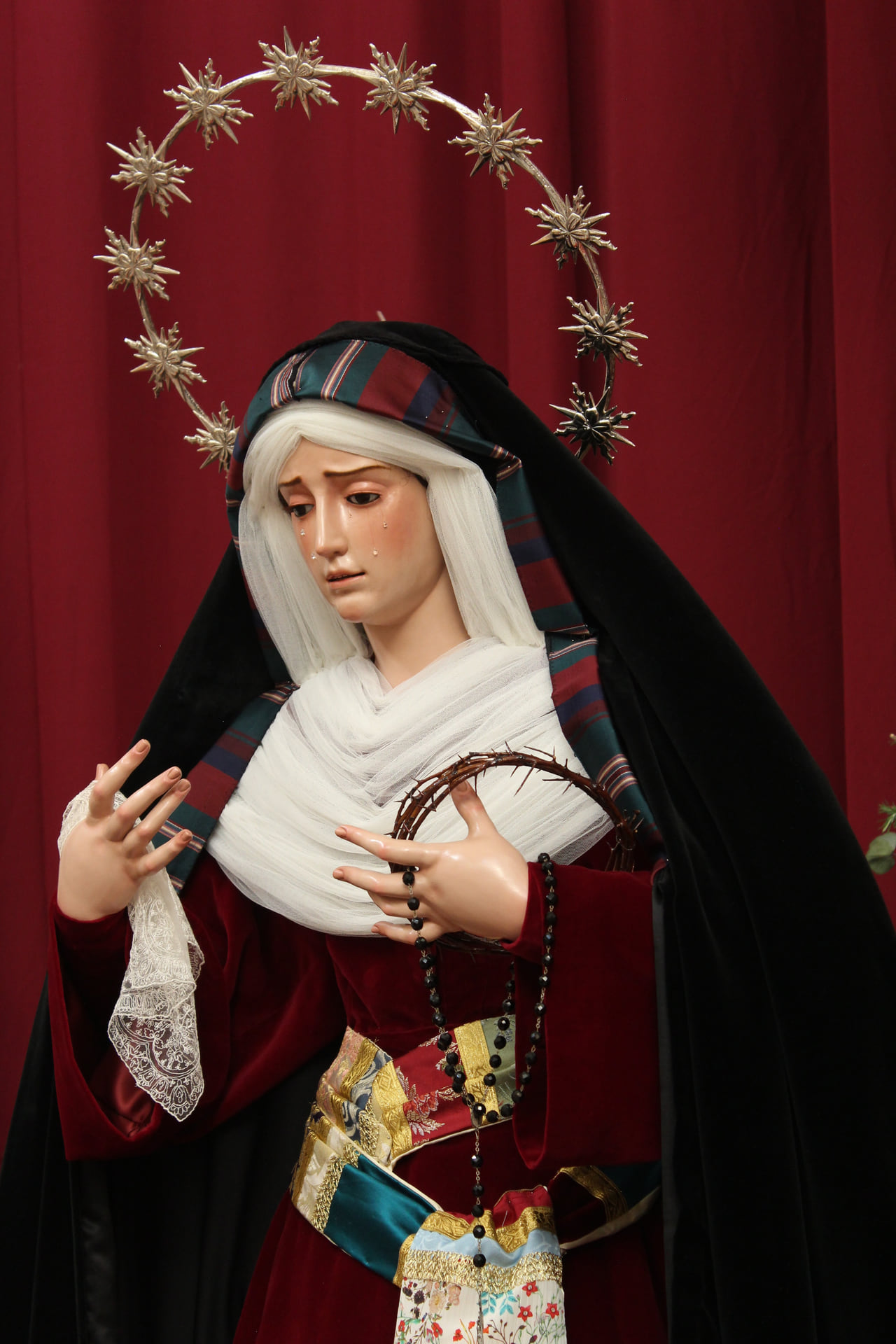 La Virgen de los Dolores, con lágrimas en el rostro, sostiene la corona de espinas y un rosario de cuentas negras